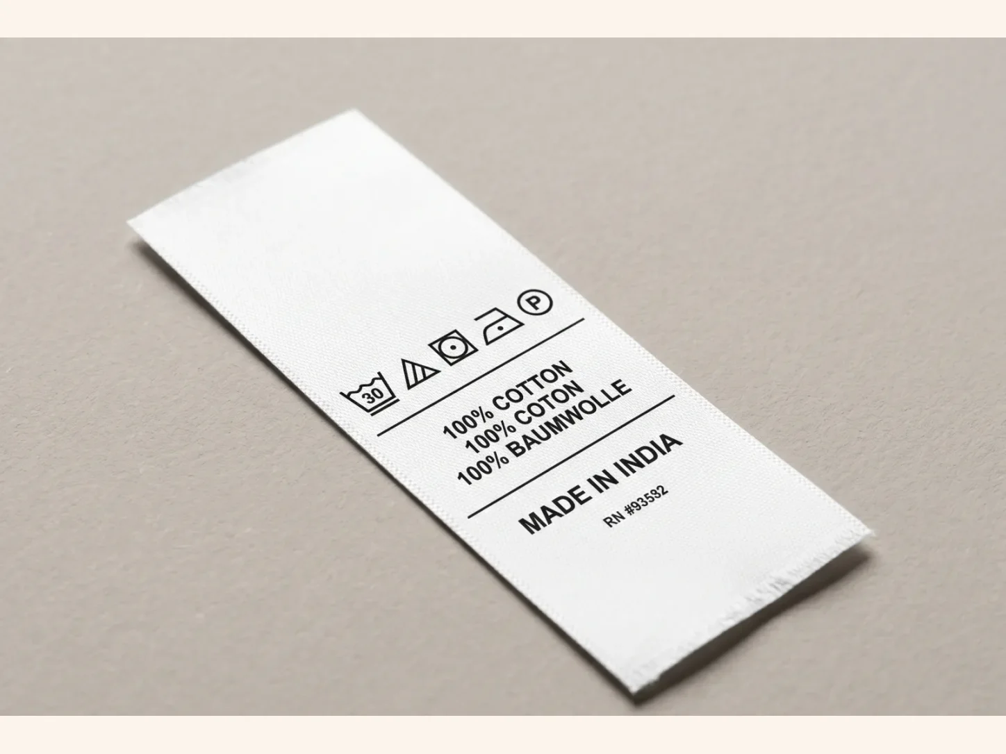 A white garment information label photographed with fibre-content text and readable wash-care symbols.
