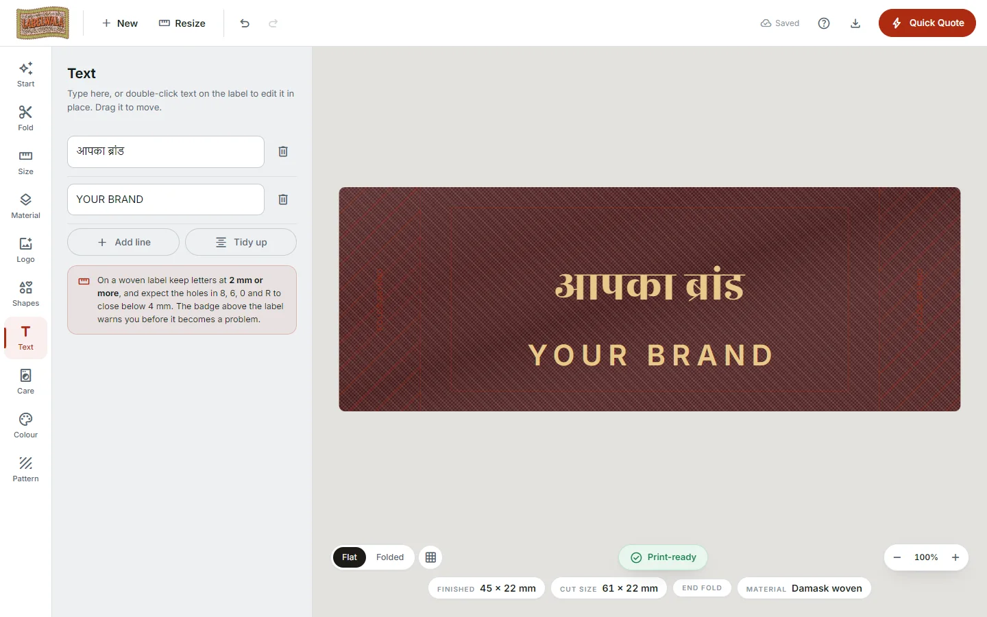 The designer's Text panel with two editable lines, one in Devanagari reading aapka brand and one reading YOUR BRAND, beside the maroon and gold label on the canvas, with a note that woven letters should be 2 mm or more