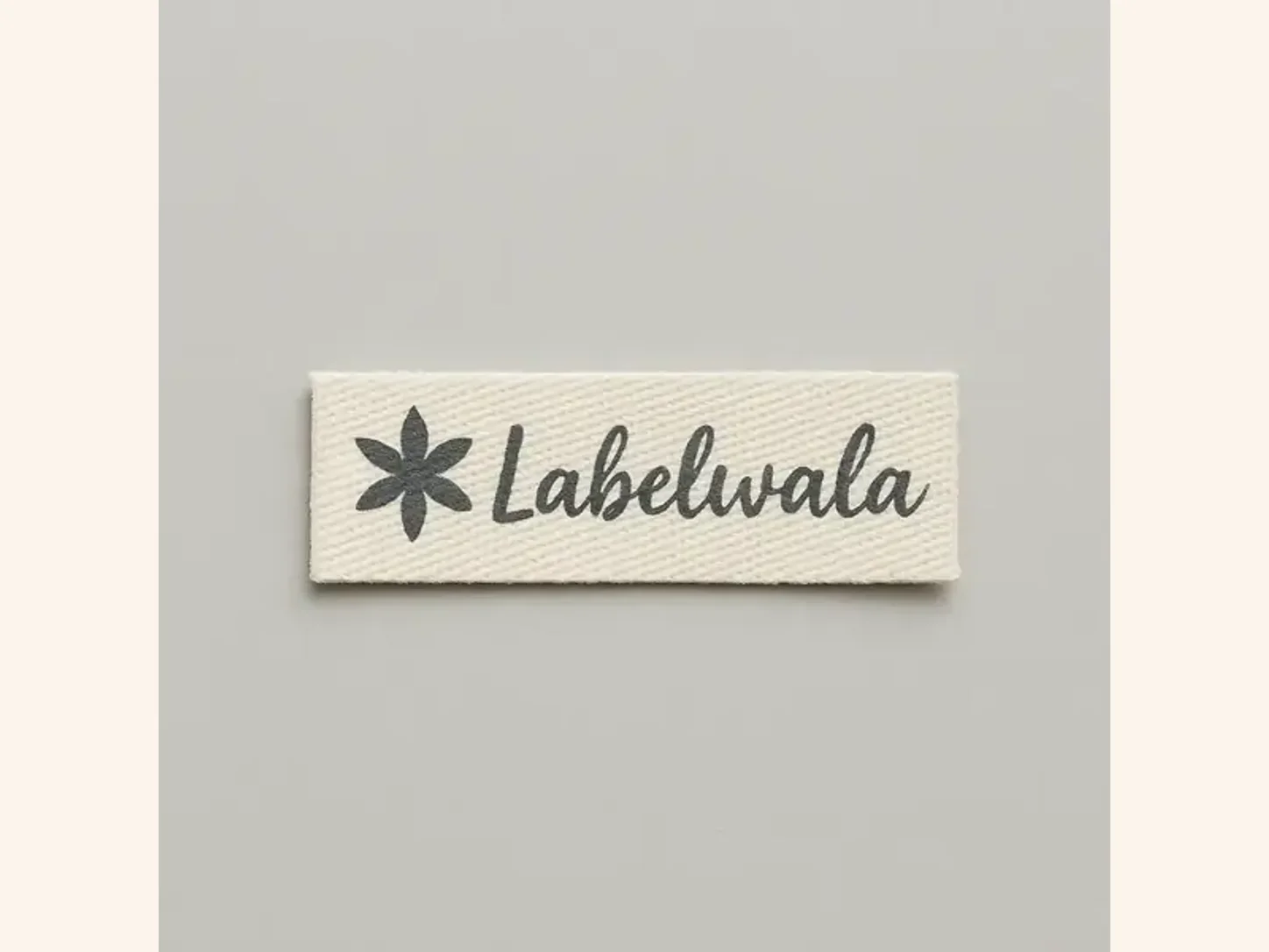 A flat cream clothing label photographed with its full rectangular face and finished edges visible.