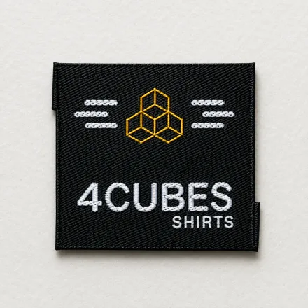 4Cubes Shirts black woven brand label with white wordmark, yellow geometric cubes logo and decorative stitched detailing, apparel brand woven label sample