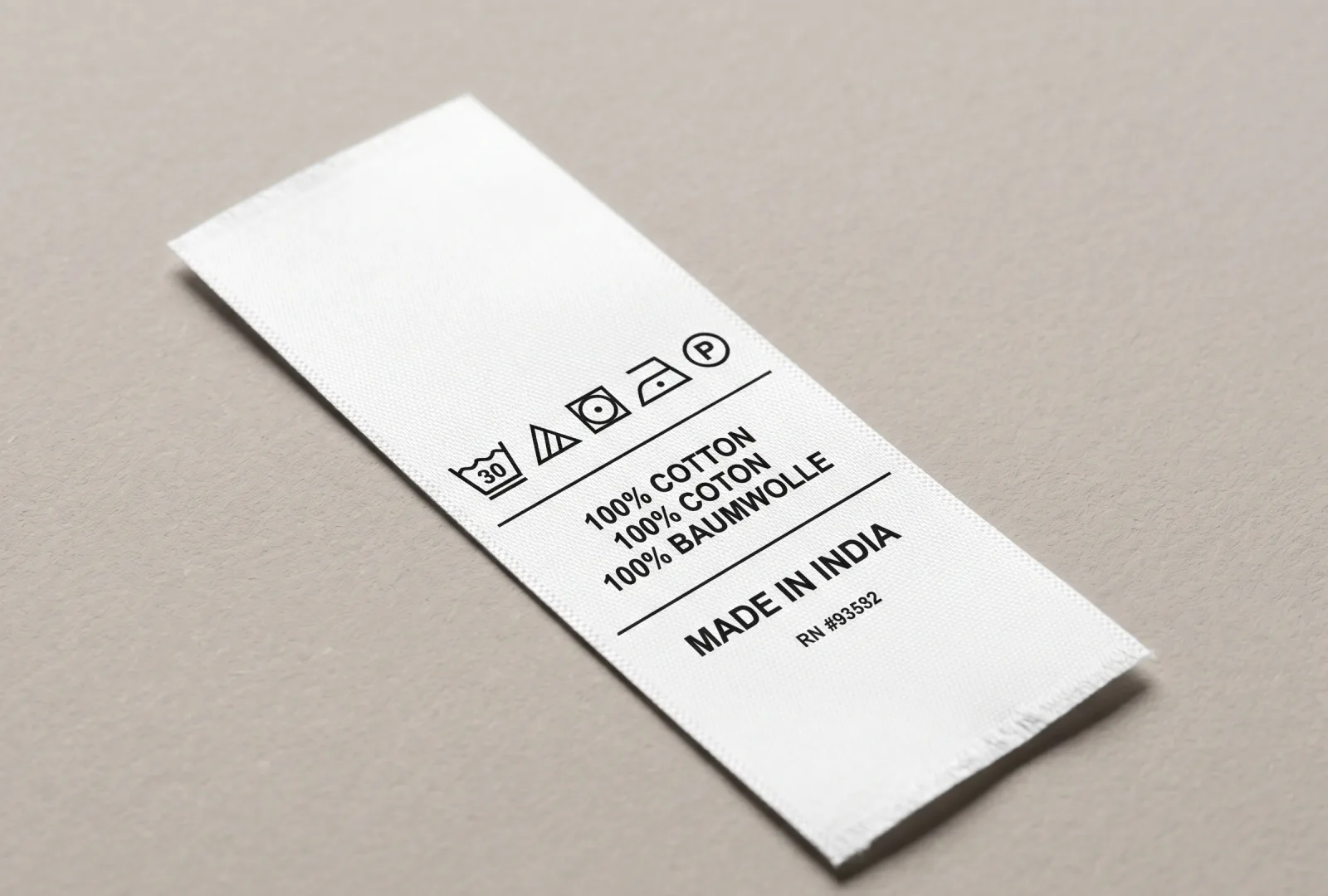 White taffeta care label printed with multilingual fibre content (English, French, German), care symbols, Made in India and RN number — example of an export-grade taffeta label